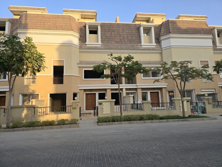 Long row of townhouses behind street trees at Sarai, New Cairo