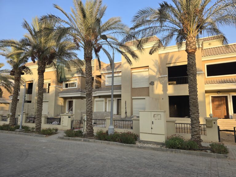 Palms and townhouse facades in late afternoon light at Sarai, New Cairo