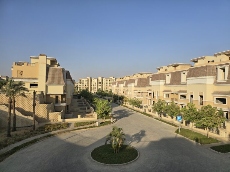 Rows of townhouses along a wide paved street at Sarai, New Cairo